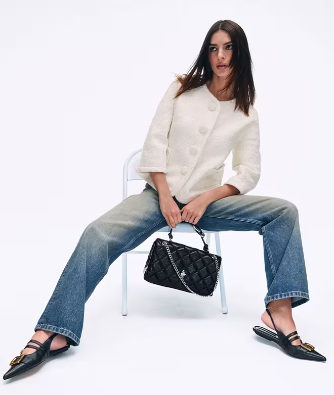 Emiliy Ratajkovski seated and holding a black dual bag